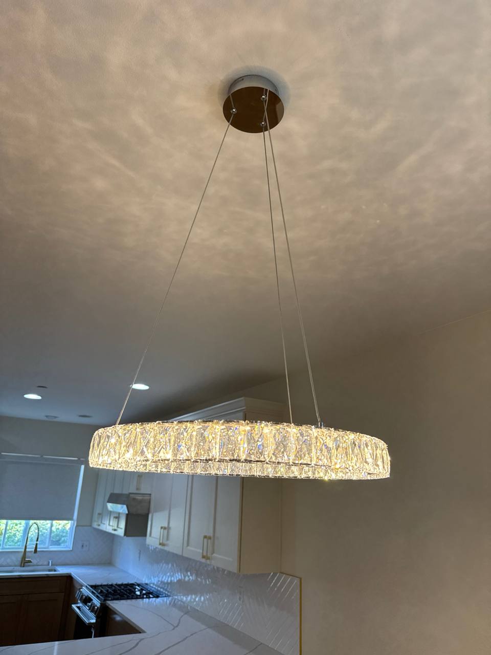 Crystal chandelier pendant light installed above modern kitchen