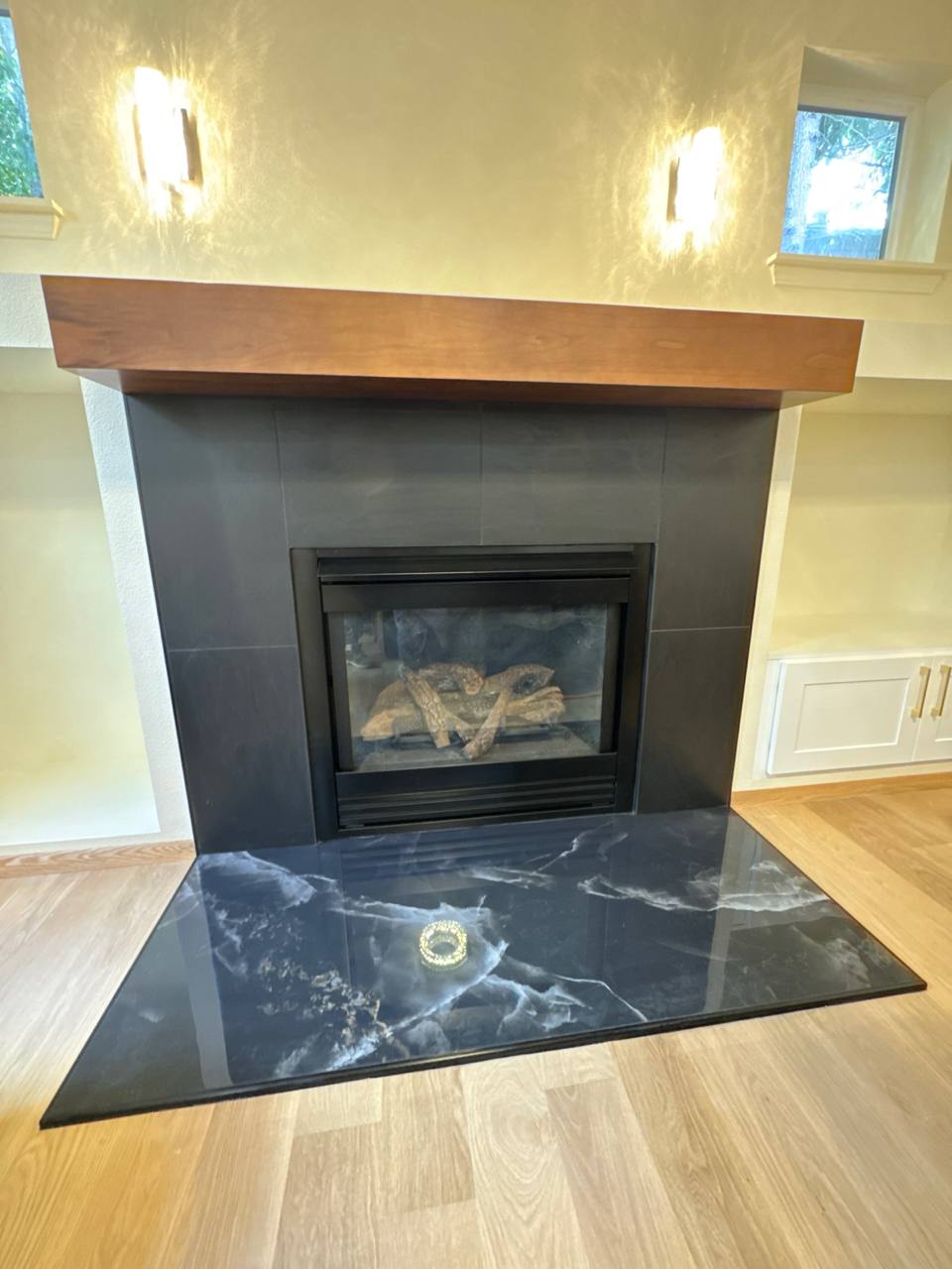 Fireplace tile installation with black marble surround and walnut wood mantel